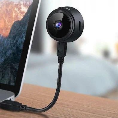 A compact wireless WiFi security camera with a black and white exterior, showing the camera itself, the magnetic mount, and a smartphone displaying the camera's view.